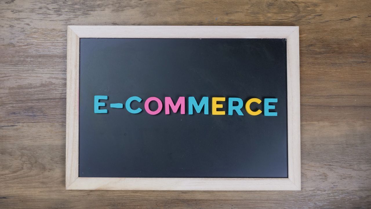 Colorful letters spelling e-commerce on a wooden framed blackboard.